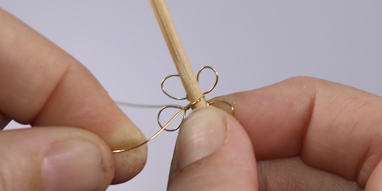 Draht nun zwei bis drei Mal um einen Zahnstocher oder eine Stricknadel wickeln. Blume aus Draht und Nagellack