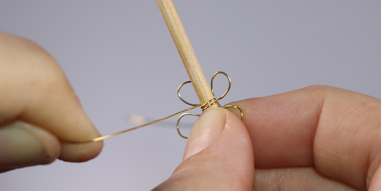 Draht nun zwei bis drei Mal um einen Zahnstocher oder eine Stricknadel wickeln. Blume aus Draht und Nagellack