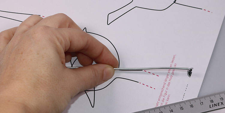 Draht entlang der Vorlage biegen, dabei unten Draht überstehen lassen. Vogel aus Aluminiumdraht biegen