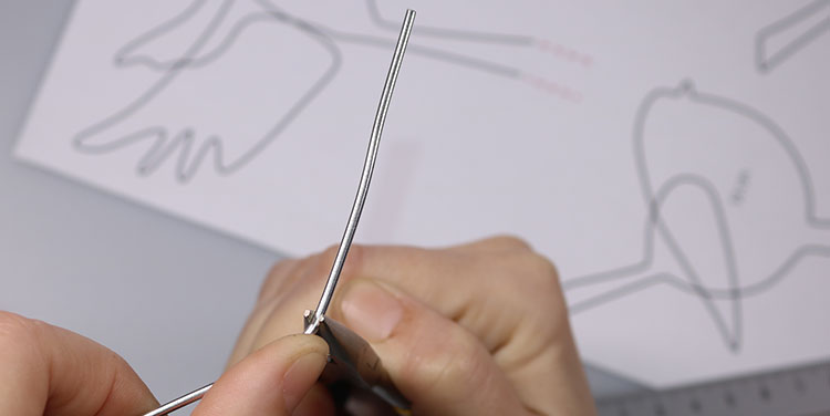 Draht mit der Zange fixieren und mit dem Daumen umbiegen. Vogel aus Aluminiumdraht biegen