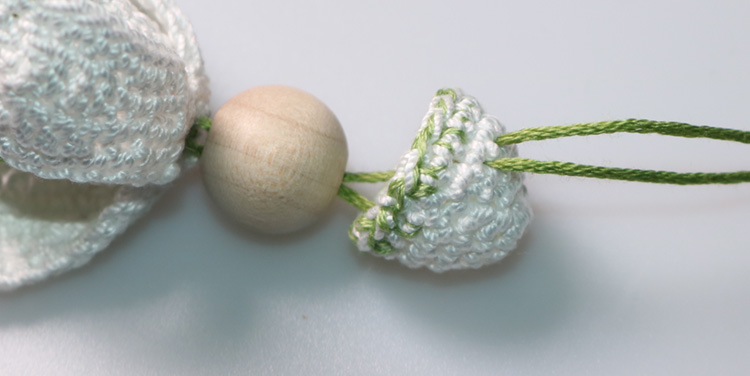 Durch das Käppchen etwas schräg durchstechen. Schneeglöckchen zusammensetzen