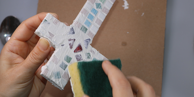 Mosaikkreuz mit dem Schwamm säubern