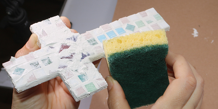 Mosaikkreuz mit dem Schwamm säubern