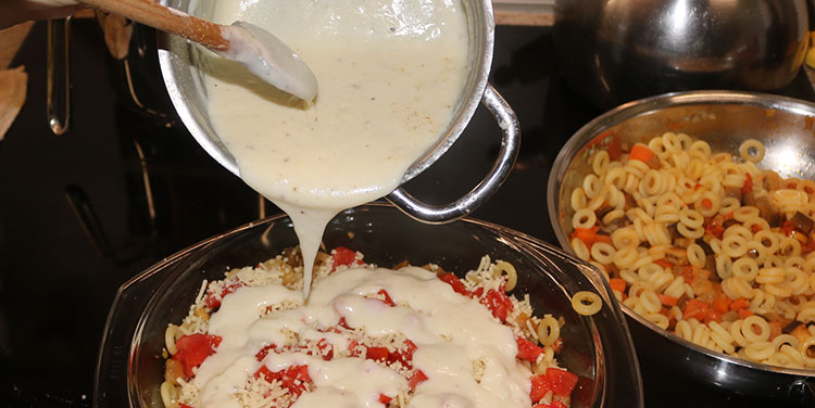 ... und die Hälfte des Béchamel darauf verteilen. Anelletti Nudelauflauf