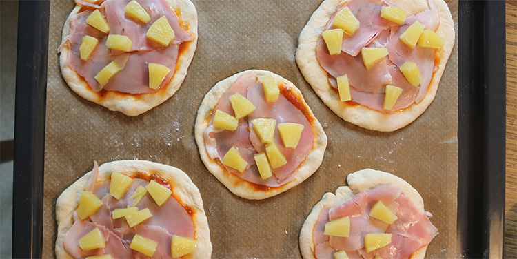 Pizza mit Ananas belegen.