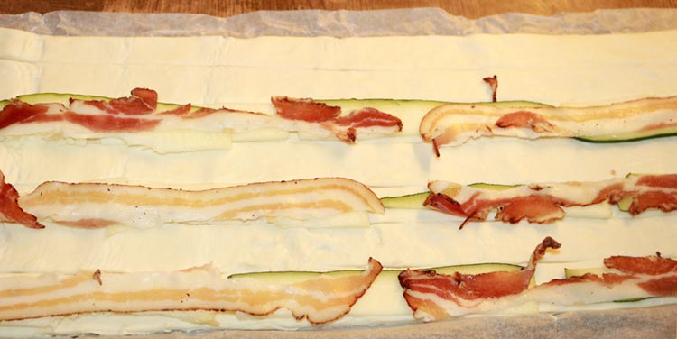 Plunderteig mit Zucchinistreifen und Speck belegen