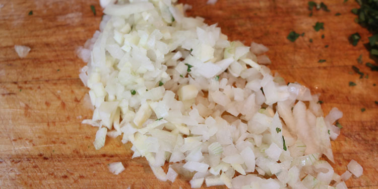 Zwiebel und Knoblauch fein schneiden. Zwiebel für Tomatensauce schneiden